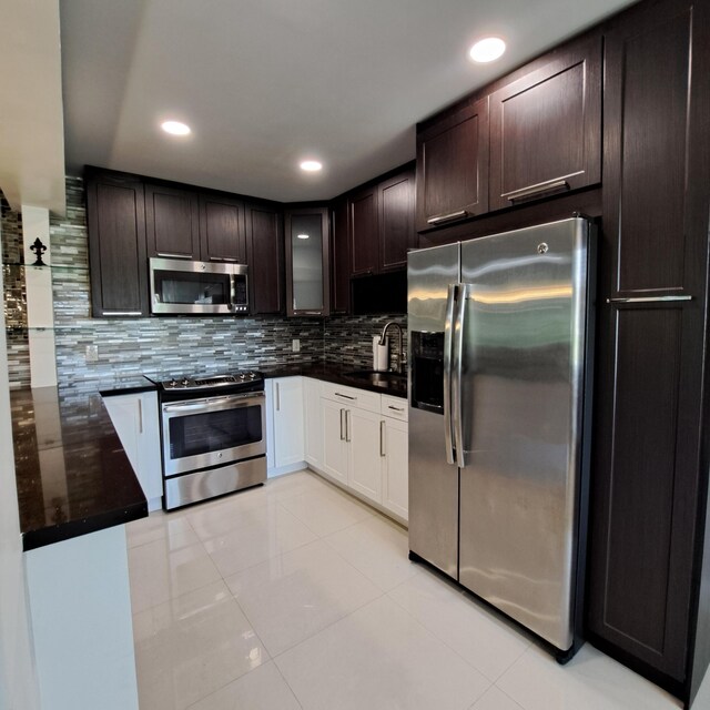 kitchen with light tile patterned floors, decorative backsplash, appliances with stainless steel finishes, sink, and dark brown cabinetry