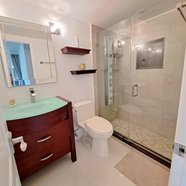 bathroom featuring toilet, vanity, a shower with shower door, and tile patterned flooring