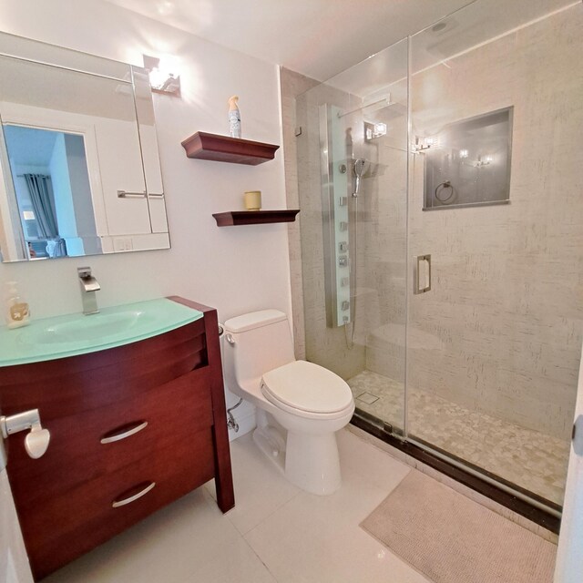 bathroom featuring tile patterned floors, vanity, walk in shower, and toilet