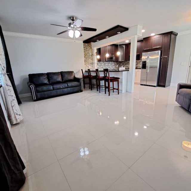 tiled living room with ceiling fan and crown molding