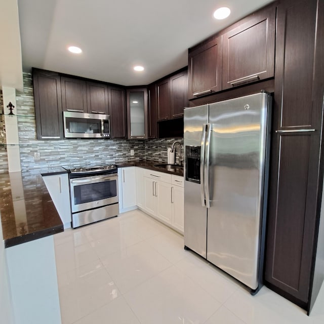 kitchen with dark brown cabinets, light tile patterned flooring, backsplash, stainless steel appliances, and sink