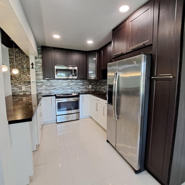 kitchen with decorative backsplash, appliances with stainless steel finishes, dark brown cabinetry, light tile patterned floors, and decorative light fixtures