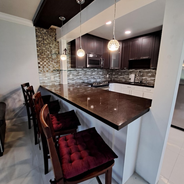 kitchen with light tile patterned floors, kitchen peninsula, hanging light fixtures, and decorative backsplash