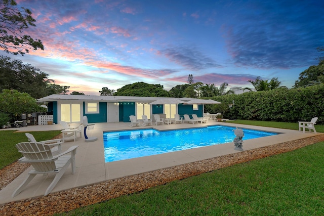 pool at dusk featuring a yard and a patio area