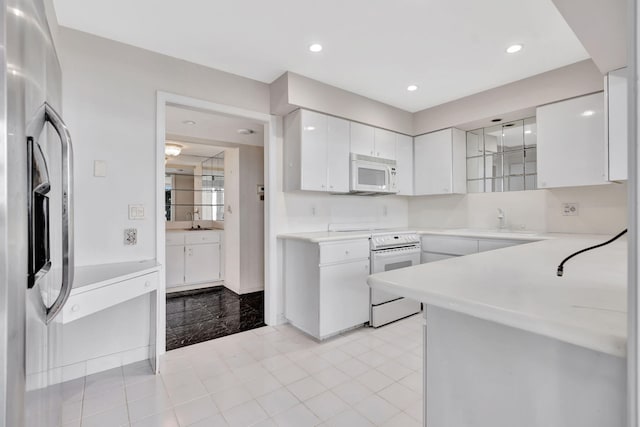 kitchen with range, stainless steel refrigerator, sink, and white cabinets