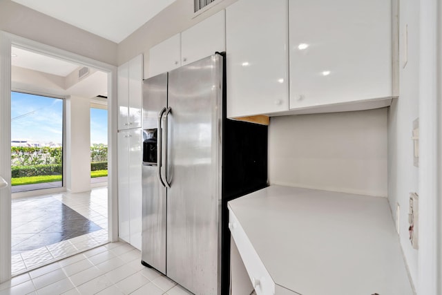 kitchen with white cabinets, stainless steel fridge with ice dispenser, and light tile patterned floors