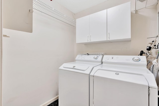 washroom featuring a textured ceiling, washing machine and dryer, and cabinets