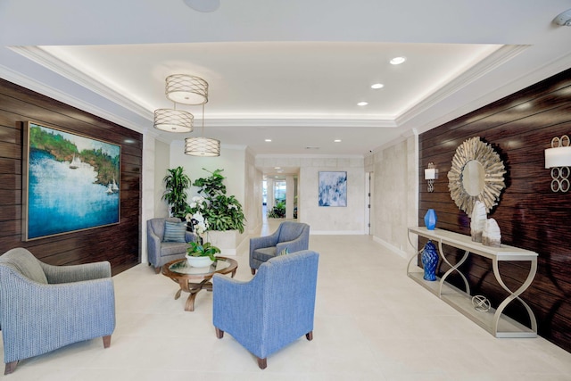 living room with a raised ceiling, ornamental molding, and wooden walls