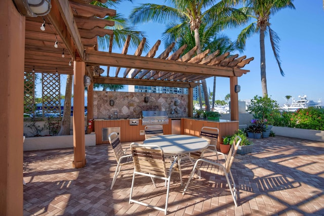 view of patio with exterior kitchen, a grill, and a pergola