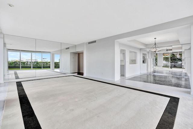 empty room with a notable chandelier and carpet floors