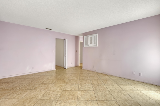 unfurnished room featuring light tile patterned flooring and a textured ceiling