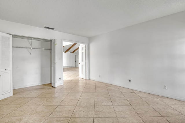 unfurnished bedroom with light tile patterned flooring, a textured ceiling, and a closet