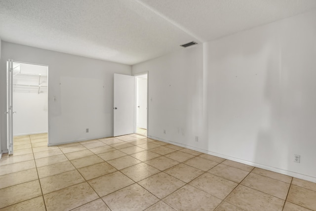 empty room featuring a textured ceiling and light tile patterned floors