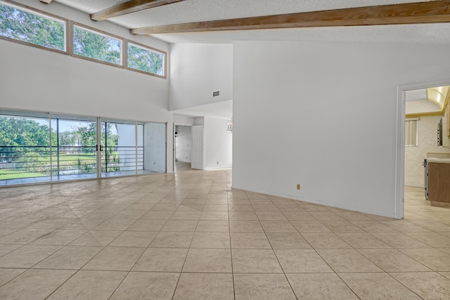 spare room featuring beamed ceiling, light tile patterned flooring, and a high ceiling