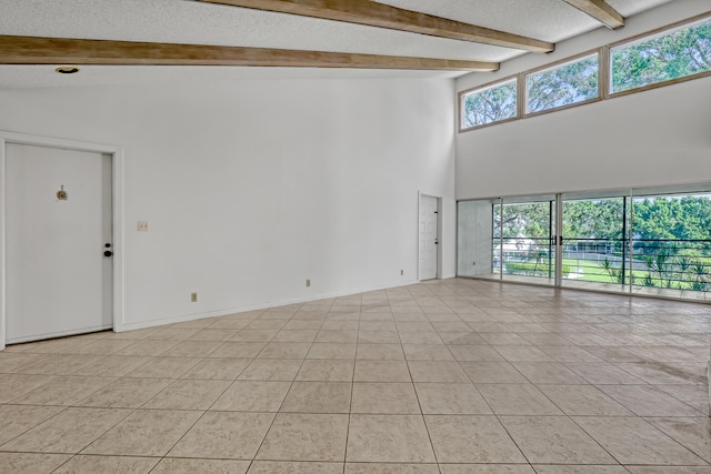 tiled empty room with beam ceiling and high vaulted ceiling