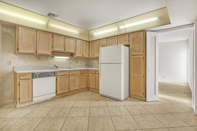 kitchen featuring white appliances, sink, light tile patterned flooring, and light brown cabinetry