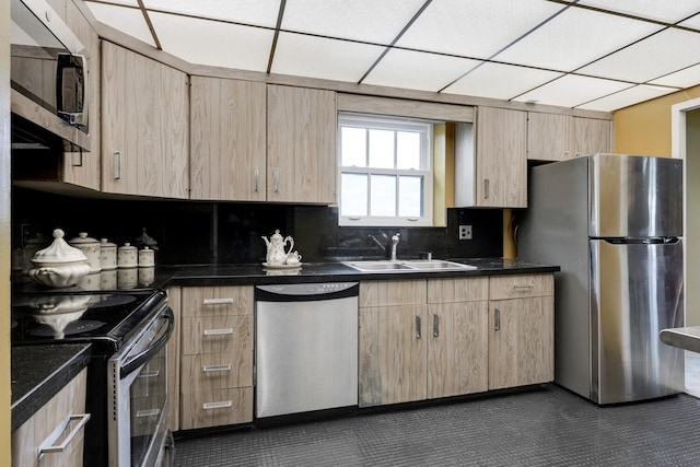 kitchen featuring dark countertops, stainless steel appliances, a sink, and light brown cabinetry