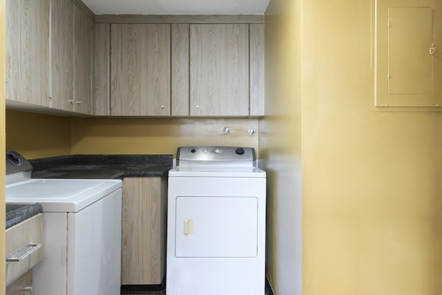 clothes washing area featuring washer and clothes dryer, cabinet space, and electric panel