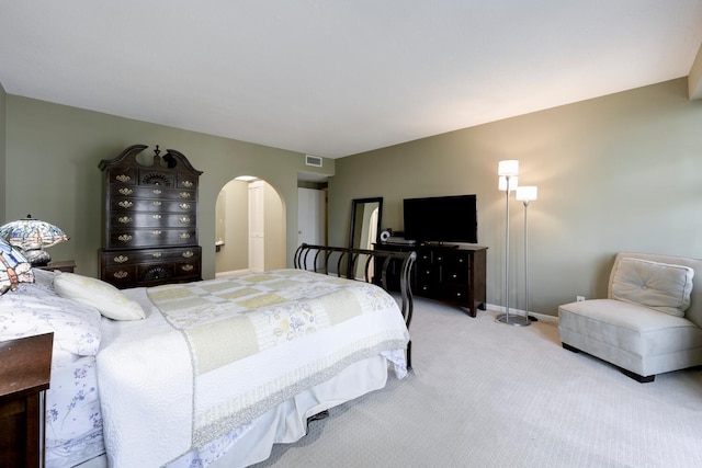 carpeted bedroom featuring arched walkways and baseboards