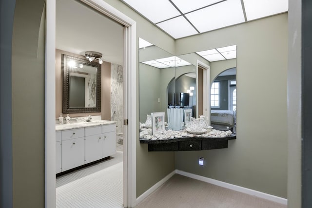 ensuite bathroom featuring ensuite bath, baseboards, and vanity