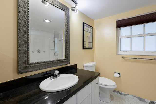 bathroom featuring toilet, vanity, and a shower with door