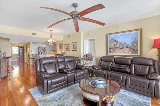 living room featuring visible vents, ceiling fan with notable chandelier, and light wood-style floors