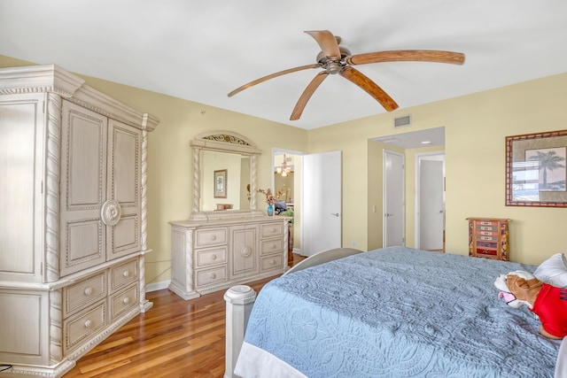 bedroom with light wood finished floors, visible vents, baseboards, and a ceiling fan