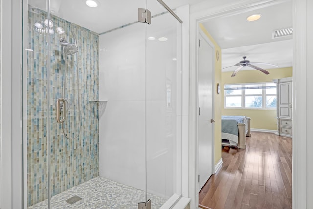 ensuite bathroom featuring visible vents, a shower stall, connected bathroom, wood finished floors, and a ceiling fan