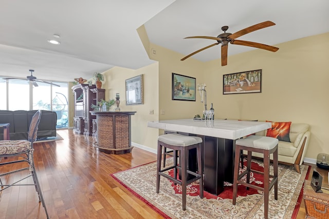 dining room with baseboards, a dry bar, expansive windows, wood finished floors, and a ceiling fan