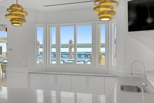 room details featuring a water view, an inviting chandelier, and a sink