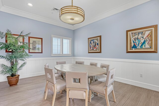 dining space featuring crown molding, wainscoting, visible vents, and light wood-type flooring