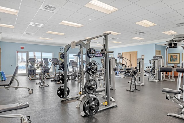 gym with a paneled ceiling, visible vents, and baseboards