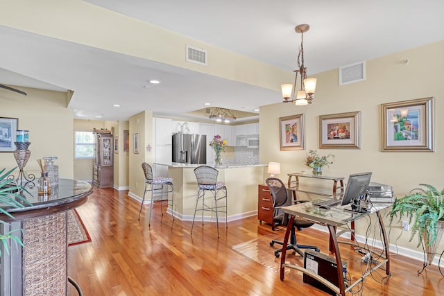 office area with light wood-style flooring, baseboards, and visible vents