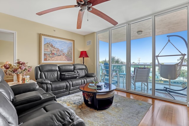 living area with floor to ceiling windows, visible vents, and wood-type flooring