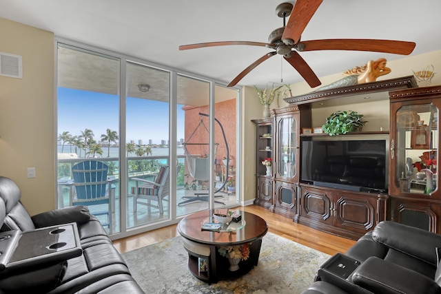 living area featuring visible vents, wood finished floors, a ceiling fan, and expansive windows