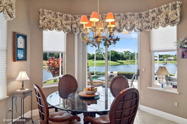 dining area featuring light tile patterned flooring, a water view, and an inviting chandelier