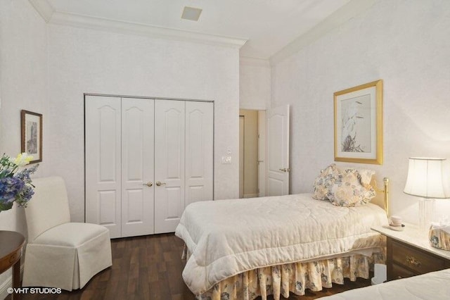 bedroom featuring dark hardwood / wood-style flooring, ornamental molding, and a closet