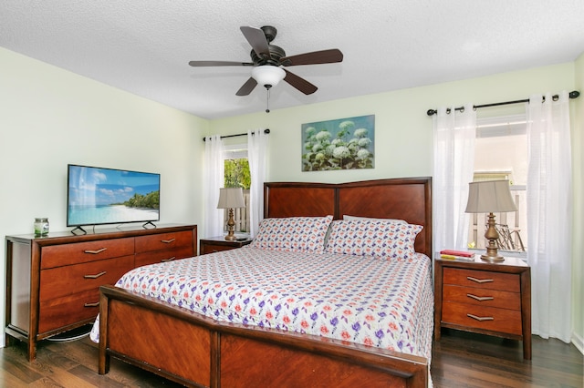 bedroom with ceiling fan, dark wood-type flooring, and a textured ceiling