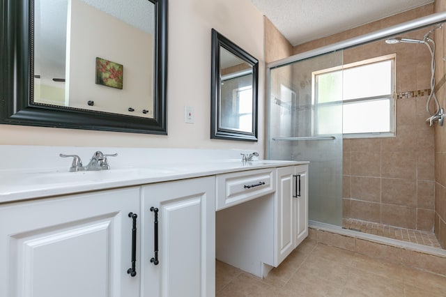 bathroom featuring a textured ceiling, dual bowl vanity, a tile shower, and tile patterned floors