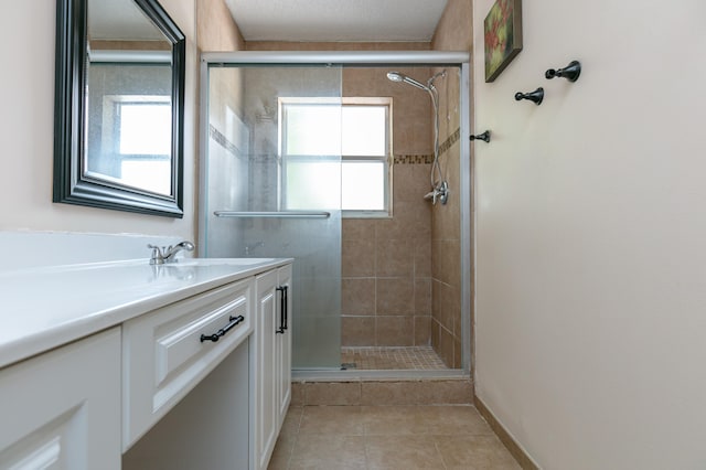 bathroom with tile patterned floors, vanity, a wealth of natural light, and an enclosed shower