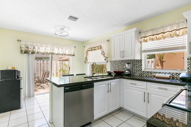 kitchen with kitchen peninsula, white cabinets, stainless steel dishwasher, tasteful backsplash, and sink