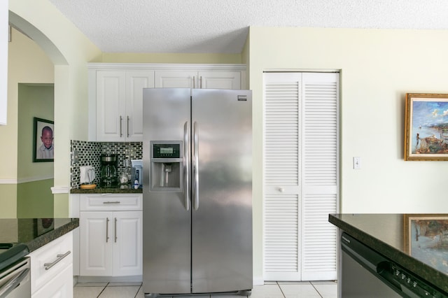 kitchen with stainless steel appliances, a textured ceiling, light tile patterned floors, decorative backsplash, and white cabinets