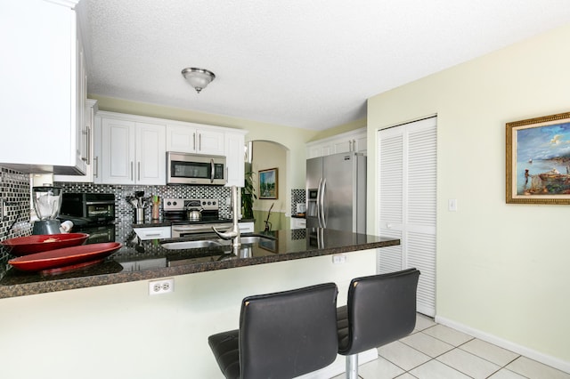 kitchen featuring appliances with stainless steel finishes, backsplash, kitchen peninsula, and light tile patterned floors