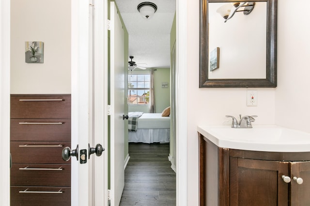 bathroom with ceiling fan, wood-type flooring, vanity, and a textured ceiling