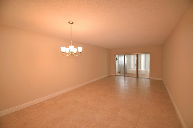 tiled empty room with a textured ceiling and an inviting chandelier