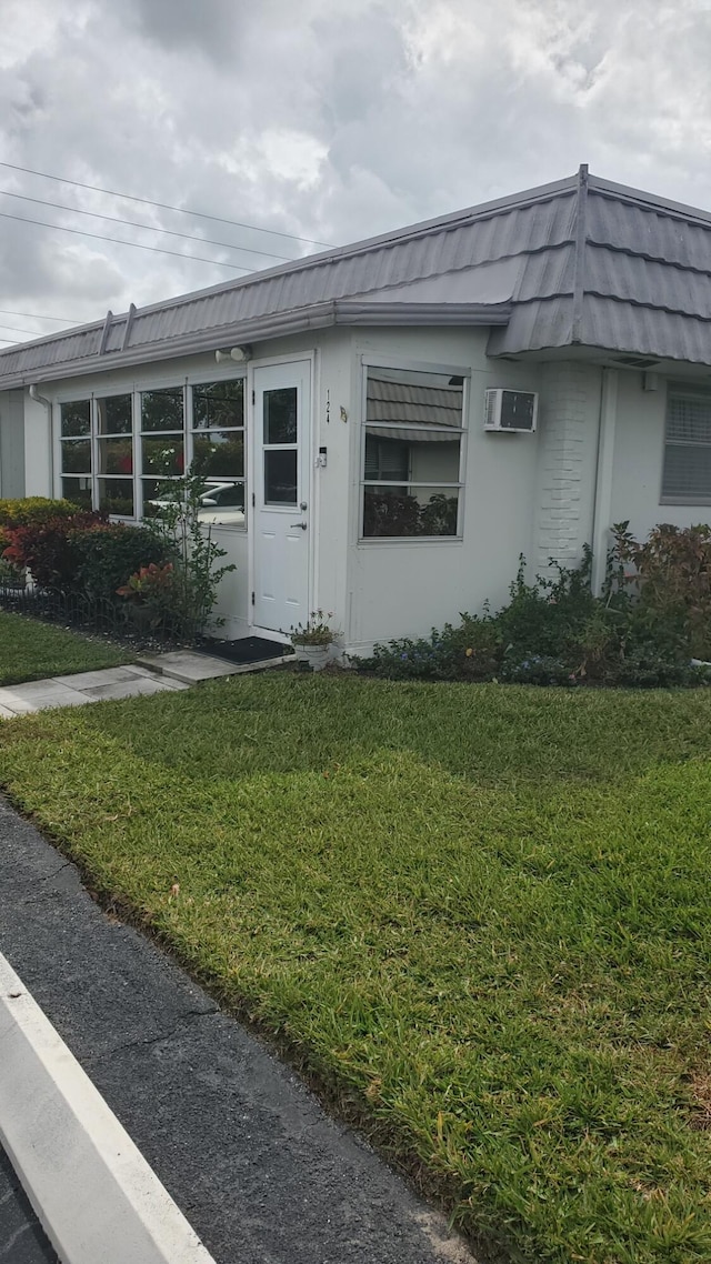 view of front of house featuring a wall mounted air conditioner and a front yard