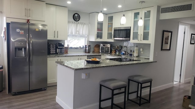 kitchen featuring decorative backsplash, appliances with stainless steel finishes, white cabinets, dark wood-type flooring, and dark stone countertops