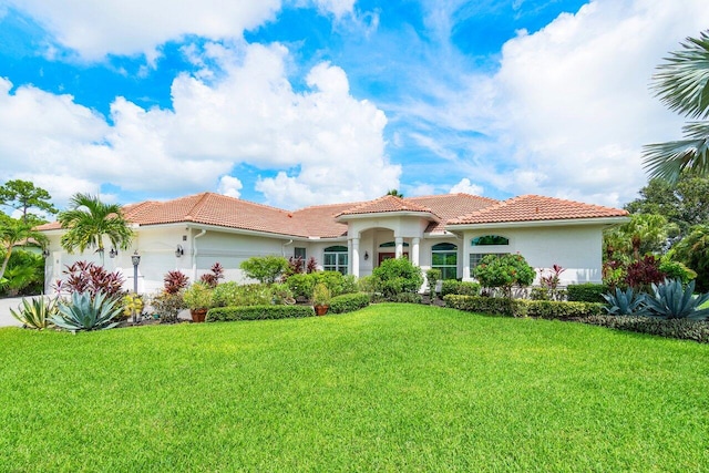 mediterranean / spanish home with a garage and a front lawn