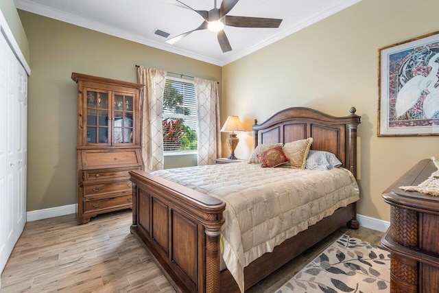 bedroom with ornamental molding, light hardwood / wood-style flooring, ceiling fan, and a closet