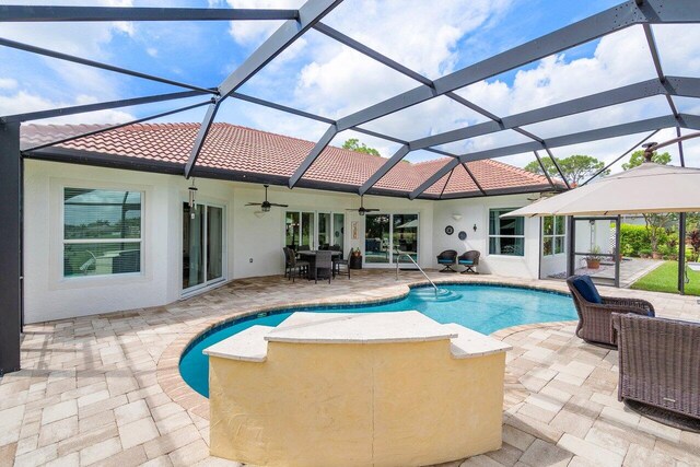 view of swimming pool featuring glass enclosure, ceiling fan, and a patio